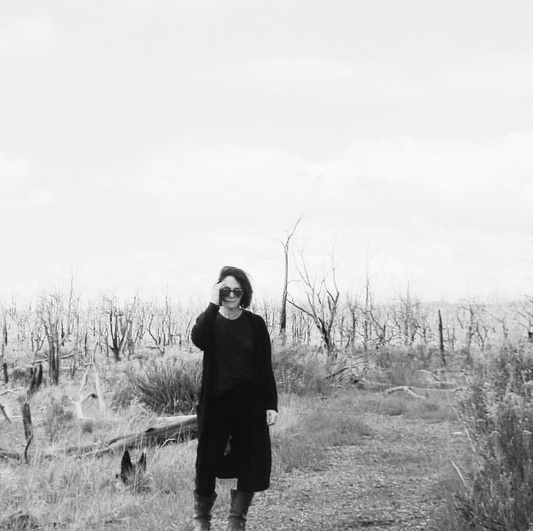 Black and white image of person standing in a barren field.